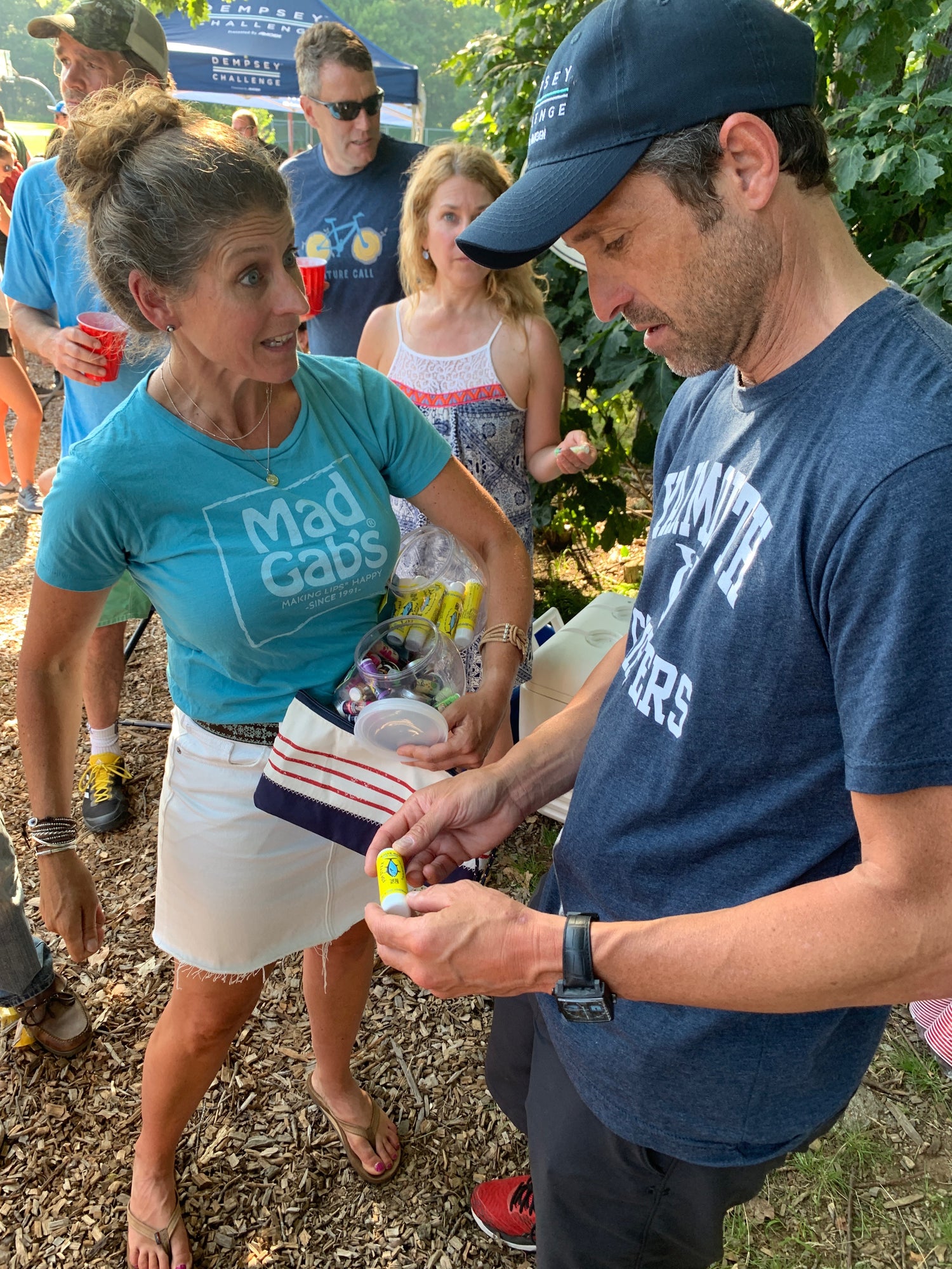 Woman talking to man among a group of people outdoors at an event