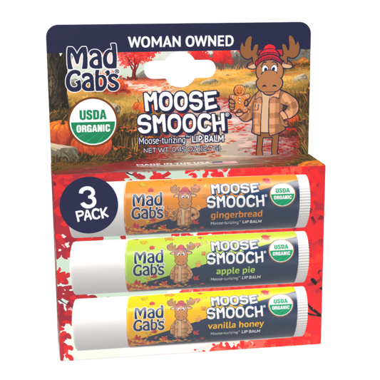 Mad Gab's Moose Smoother lip balm 3-pack in its original retail cardboard display box. The packaging features a cartoon moose in an autumn setting and highlights three flavors: gingerbread, apple pie, and vanilla honey, all with USDA Organic certification seals.